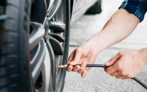 Mani che gonfiano uno pneumatico. Evitare pneumatici troppo gonfi conseguenze: usura irregolare e minore aderenza.