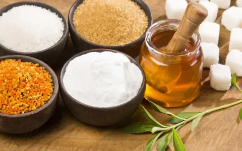 Schalen mit Zucker, Honig, Pollen und Stevia-Blättern – ideale Zutaten für zuckerersatz zum Backen.