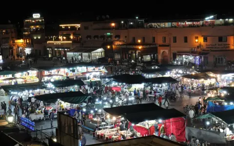 Belebter Marktplatz in Marokko bei Nacht. Viele Stände mit Lichtern und Menschen, die einkaufen und essen. Wann ist Ramadan in Marokko?