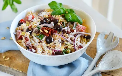 En härlig italiensk pastasallad med rotfrukter, oliver, soltorkade tomater och pinjenötter, toppad med färsk basilika.