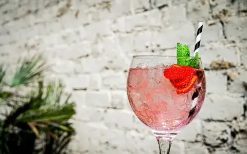 Orzeźwiający pink gin z lodem, truskawką i miętą, idealny na letnie popołudnie.