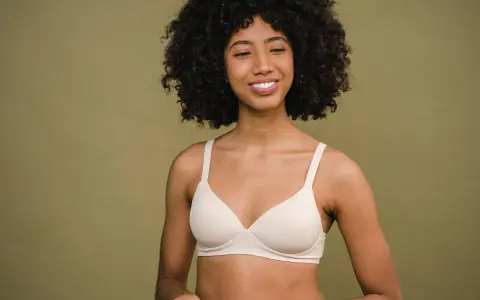 Donna sorridente con un reggiseno color carne. Un reggiseno troppo stretto conseguenze possono essere scomode, ma questo sembra comodo.