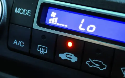 El aire acondicionado del coche muestra "Lo" indicando baja temperatura. El ventilador está al mínimo y la luz roja está encendida.