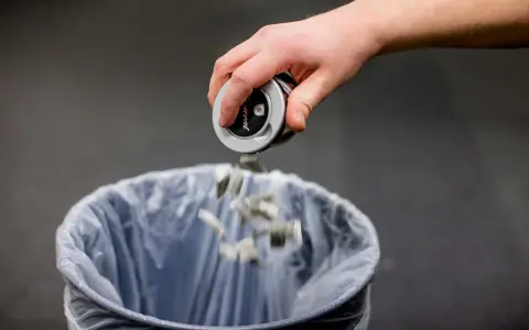 En hand tömmer snusdosan i en papperskorg. Ett steg för att sluta snusa.