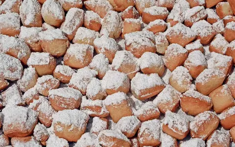 Ein Haufen goldbrauner, puderzuckerbestäubter Schmalzkuchen, die an ein schmalzkuchen originalrezept erinnern.