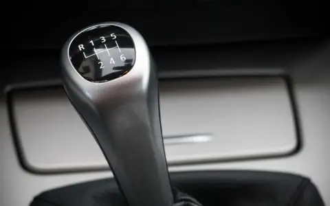 Palanca de cambios de un coche manual, con el patrón de marchas visible. Parece que el cambio de marchas roto impide seleccionar la marcha deseada.