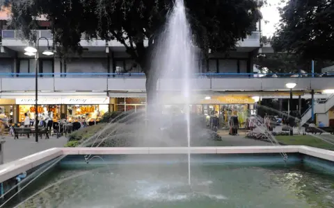 Fontana z fontanną w centrum Lido di Savio, z widokiem na sklepy i drzewa.