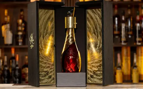 Elegancka, złota butelka z 30 letnią whisky Eagle Rare w ozdobnym, drewnianym pudełku z motywem piór.