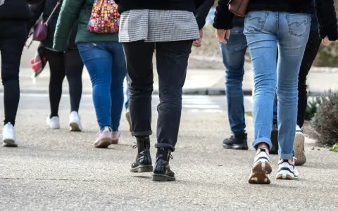 En grupp människor går på en trottoar. De har på sig jeans och sneakers. Kanske är de på väg att nå sina 10000 steg kcal.