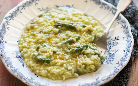 Un cremoso risotto agli asparagi, servito in un piatto decorato, pronto per essere gustato.