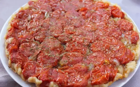 Tarte tatin di pomodorini confit, con cipolle caramellate e erbe aromatiche, un tripudio di sapori mediterranei.