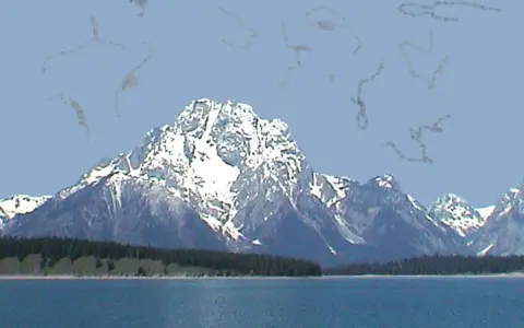 Montagne innevate su uno sfondo azzurro, con strani pallini negli occhi che fluttuano nell'aria.