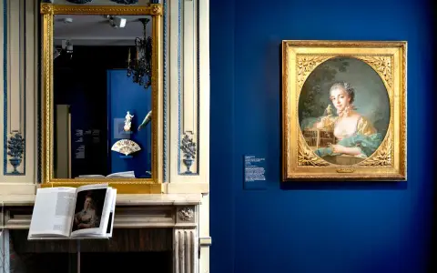 Portrait d'une jeune femme par un peintre français moderne, exposé dans un musée. Un livre ouvert sur une cheminée reflète l'œuvre.