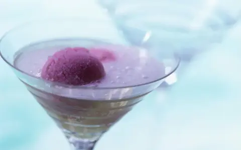 Ein erfrischendes Eis mit Sekt in einem Martiniglas. Die pinke Eiskugel schwimmt in prickelndem Sekt, ein Genuss für heiße Tage.