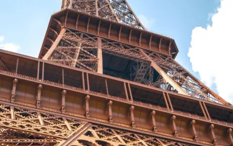 La famille Eiffel, une fortune bâtie sur le fer. Vue rapprochée de la Tour Eiffel, structure métallique complexe sous un ciel bleu.
