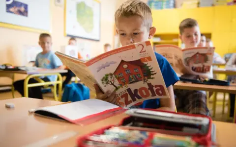 Chłopiec z zapałem czyta podręcznik "Nasza Szkoła". To dobry start dla każdego ucznia, by z radością poznawać świat.