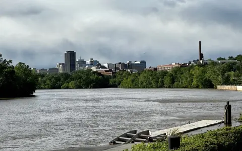A cloudy sky looms over the Richmond, VA skyline, with the James River in the foreground. This view hints at fun things to do in Richmond, VA, like kayaking or enjoying the riverfront.