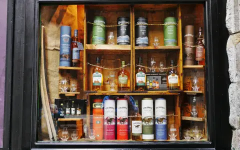 Regale voller irischer Whiskeys, darunter Connemara peated whisky, Kilbeggan und Tyrconnell. Gläser und Flaschen sind kunstvoll arrangiert.