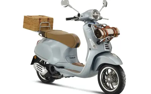 Stylowe skutery retro 125 w kolorze błękitnym, z wiklinowym koszem z tyłu i kocem z przodu, idealne na piknik.