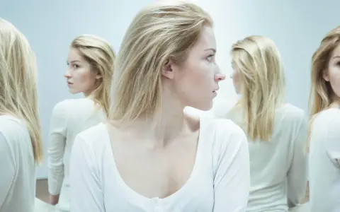 En kvinna med blont hår tittar åt sidan, omgiven av spegelbilder. En visuell representation av en kvinnlig psykopat checklista.