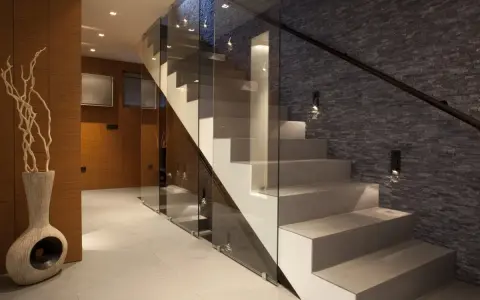 Nowoczesna klatka schodowa inspiracje: szkło, kamień i drewno tworzą elegancką przestrzeń.