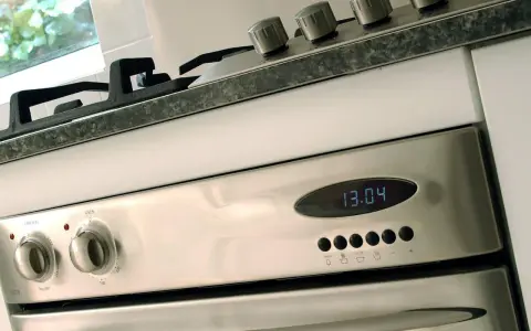 Edelstahl-Backofen mit digitaler Zeitanzeige (13:04). Die Knöpfe für Funktion und Temperatur sind sichtbar. Bereit für den ersten **Backofen einbrennen**.