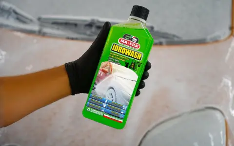 Mano con guanto nero tiene bottiglia di Idrowash, un detergente schiumoso verde brillante per auto.