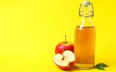 Bouteille de vinaigre de cidre et pommes rouges, un remède naturel pour l'urticaire.