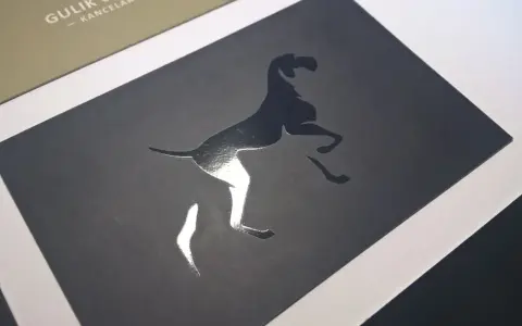 Elegancka wizytówka z psem w skoku, wykonana techniką lakierowania wybiórczego. Błyszczący pies kontrastuje z matowym tłem.