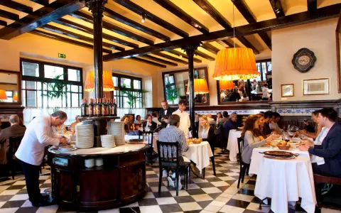 Un camarero prepara platos en un restaurante lleno de comensales. Los pasos para abrir un restaurante incluyen crear un ambiente acogedor como este.