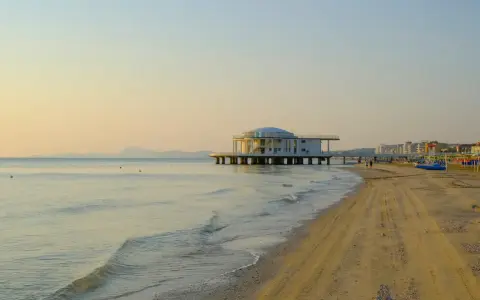 Alba dorata sul mare di Senigallia, con il celebre edificio sul mare e la spiaggia che si estende verso la città.