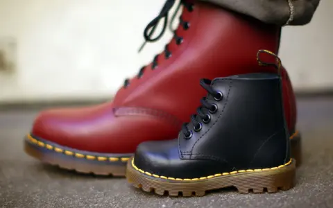 Zwei Dr. Martens Stiefel, ein roter und ein schwarzer, zeigen die Qualität des Dr. Martens Leder.