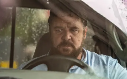 Russell Crowe bakom ratten i en bil, med regndroppar på vindrutan. En intensiv scen från filmer med Russell Crowe.