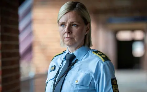 En kvinna i uniform från uniformen serie, med blå skjorta och slips, blickar ut.