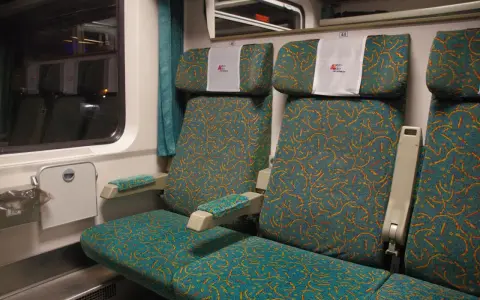 Wnętrze wagonu 4 Pendolino. Widok na dwa rzędy siedzeń z charakterystycznym wzorem.
