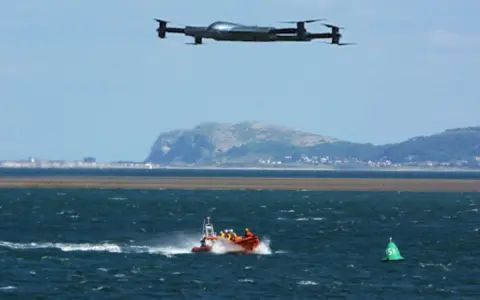 Search and rescue drones hover over a lifeboat speeding across choppy waters, assisting in a coastal operation.