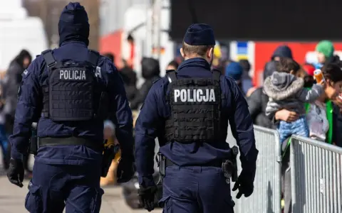 Dwóch policjantów w kamizelkach taktycznych pilnuje porządku. Chcesz wiedzieć, co trzeba zrobić, żeby zostać policjantem?