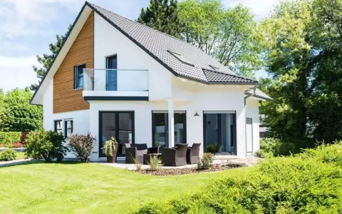 Maison moderne avec balcon, terrasse et jardin. Un projet de construction de maison qui respecte le budget.