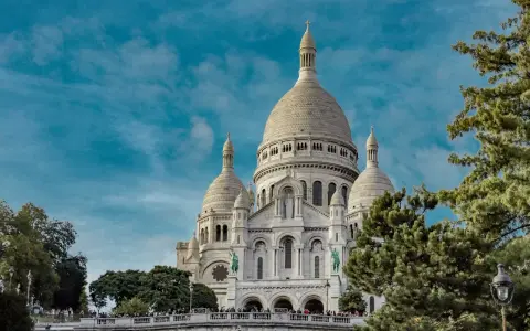 Basílica del Sacré-Cœur, uno de los monumentos de Francia, se alza majestuosa bajo un cielo azul con nubes.