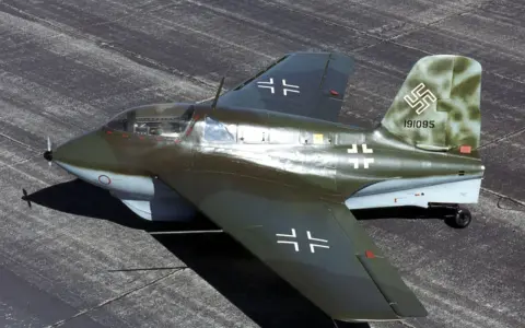 Ein Messerschmitt Me 163 Komet, ein Raketenjäger, steht auf einem Flugplatz.