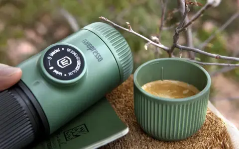 Zielona kawa w górach. Nanopresso i kubek z aromatycznym espresso na drewnianym pniu, wśród gałązek. Idealny towarzysz podróży.