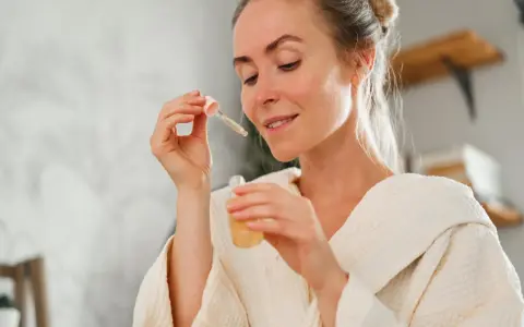 Frau mit einem Tropfen Serum in der Pipette, bereit für ihre Hautpflege-Routine. Ob Retinol oder Hyaluron, sie wählt das Beste für ihre Haut.