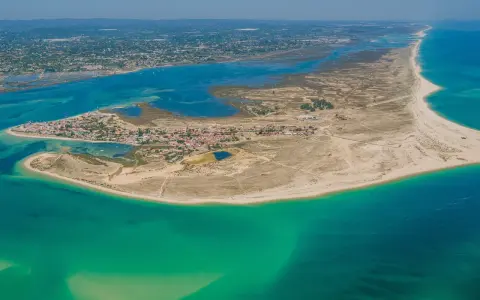 Luftaufnahme der Faro Inseln mit türkisfarbenem Wasser, Sandstränden und einer kleinen Stadt.