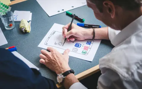 UX designer szkicuje interfejs aplikacji na papierze.