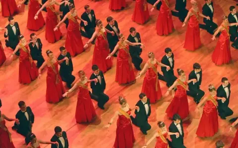 Junge Paare in roten Kleidern und schwarzen Anzügen tanzen. Die Kleiderordnung der Semperoper wird hier elegant umgesetzt.