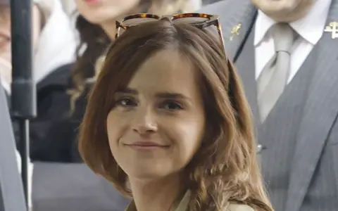 Emma Watson, con occhiali da sole sulla testa, sorride. La sua espressione suggerisce una vivacità che alcuni associano all'ADHD.
