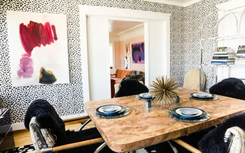 Esszimmer mit auffälliger Tapete im Jaguar Muster. Ein Holztisch mit Tellern und ein Kunstwerk an der Wand.