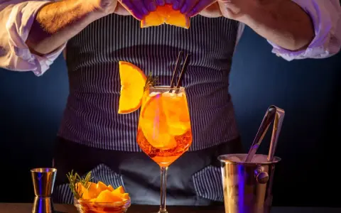 Barman prepara un Aperol Spritz, mostrando los distintos tipos de aperol y sus guarniciones.