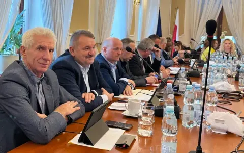Mężczyźni przy stole obradują, dyskutując o przyznaniu absolutorium.