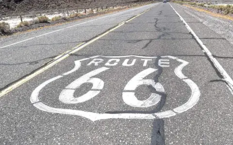 La Route 66, symbole de liberté et d'aventure, s'étend sur l'asphalte craquelé. Sa signification est immense pour les voyageurs.